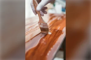 Brocha aplicando barniz sobre una superficie de madera