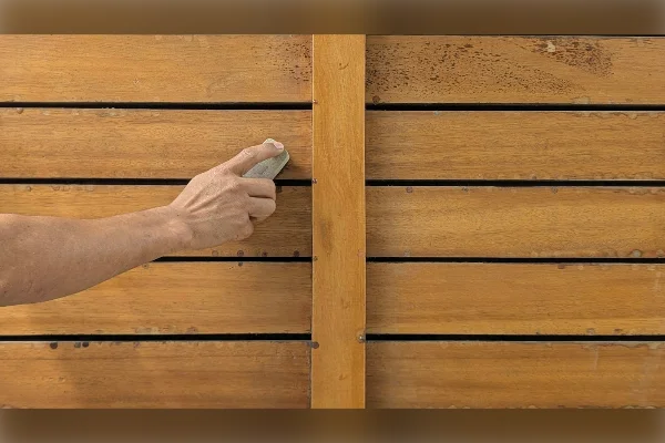 Mano lijando una tabla de madera antes de barnizar