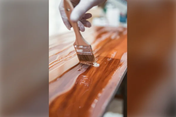 Brocha aplicando barniz sobre una superficie de madera