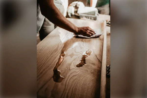 Persona limpiando una mesa de madera con un paño